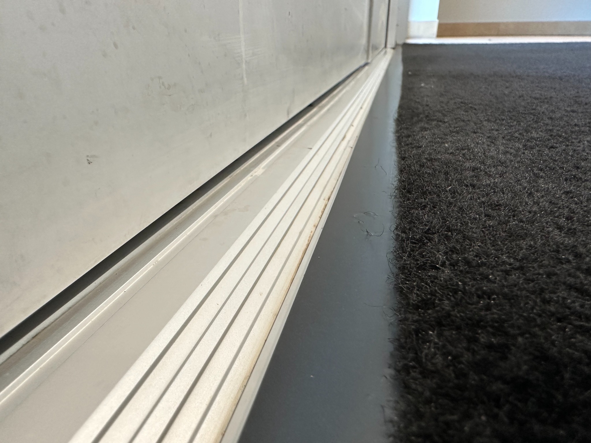 Dust accumulation in a commercial aluminum door track before detail cleaning