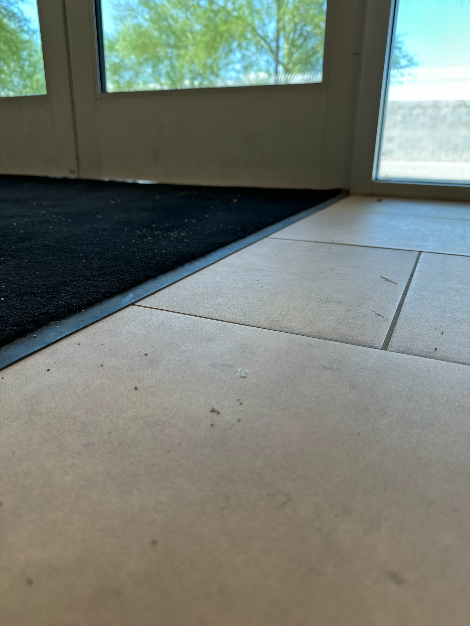 Dust and debris on tile next to a commercial entrance mat after Arizona monsoon activity