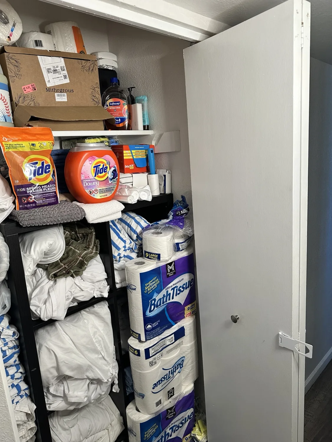Storage shelves with extra linens laundry supplies and paper products
